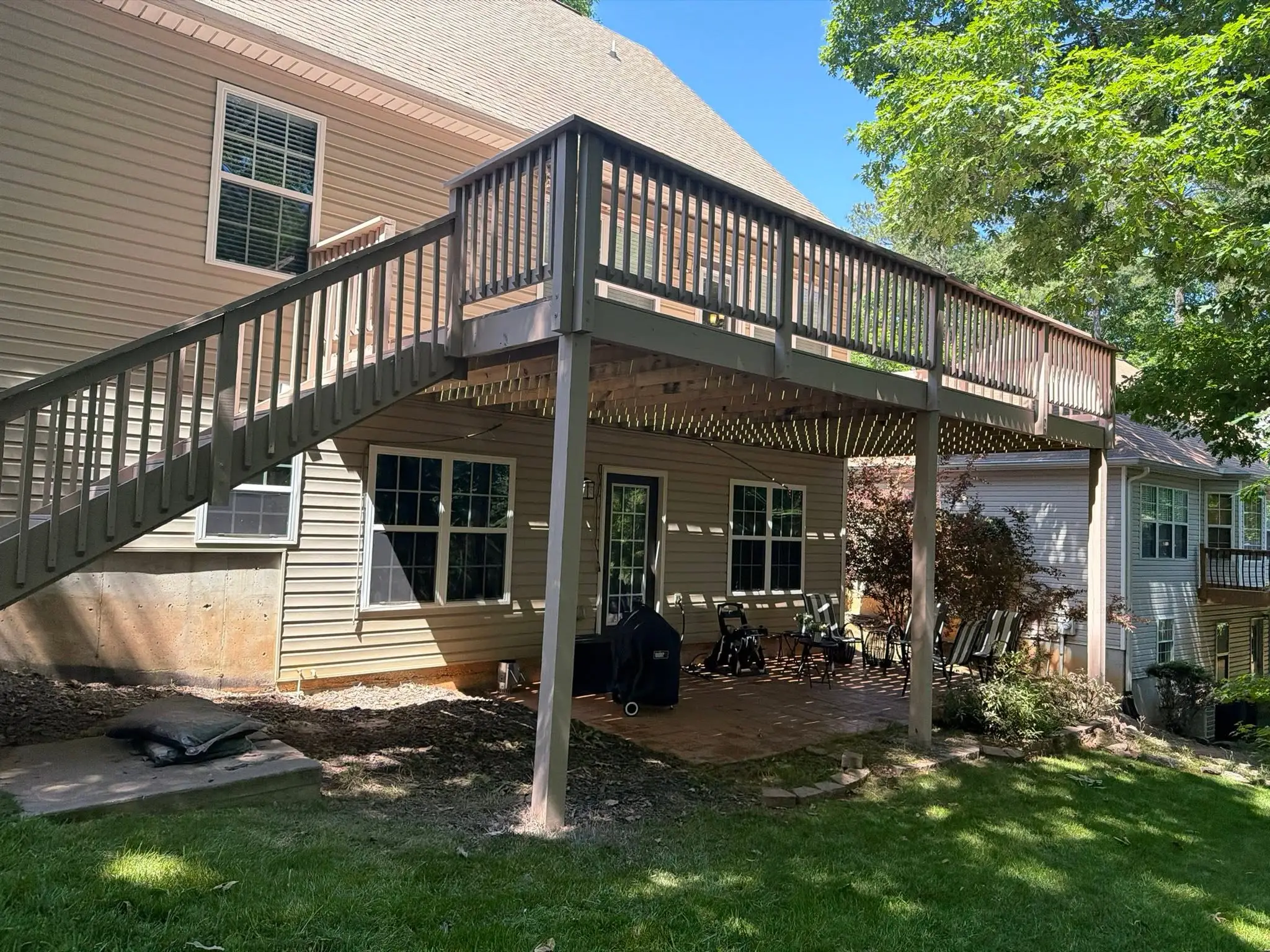 Stained second-story deck with stairs down to a brick patio under the deck