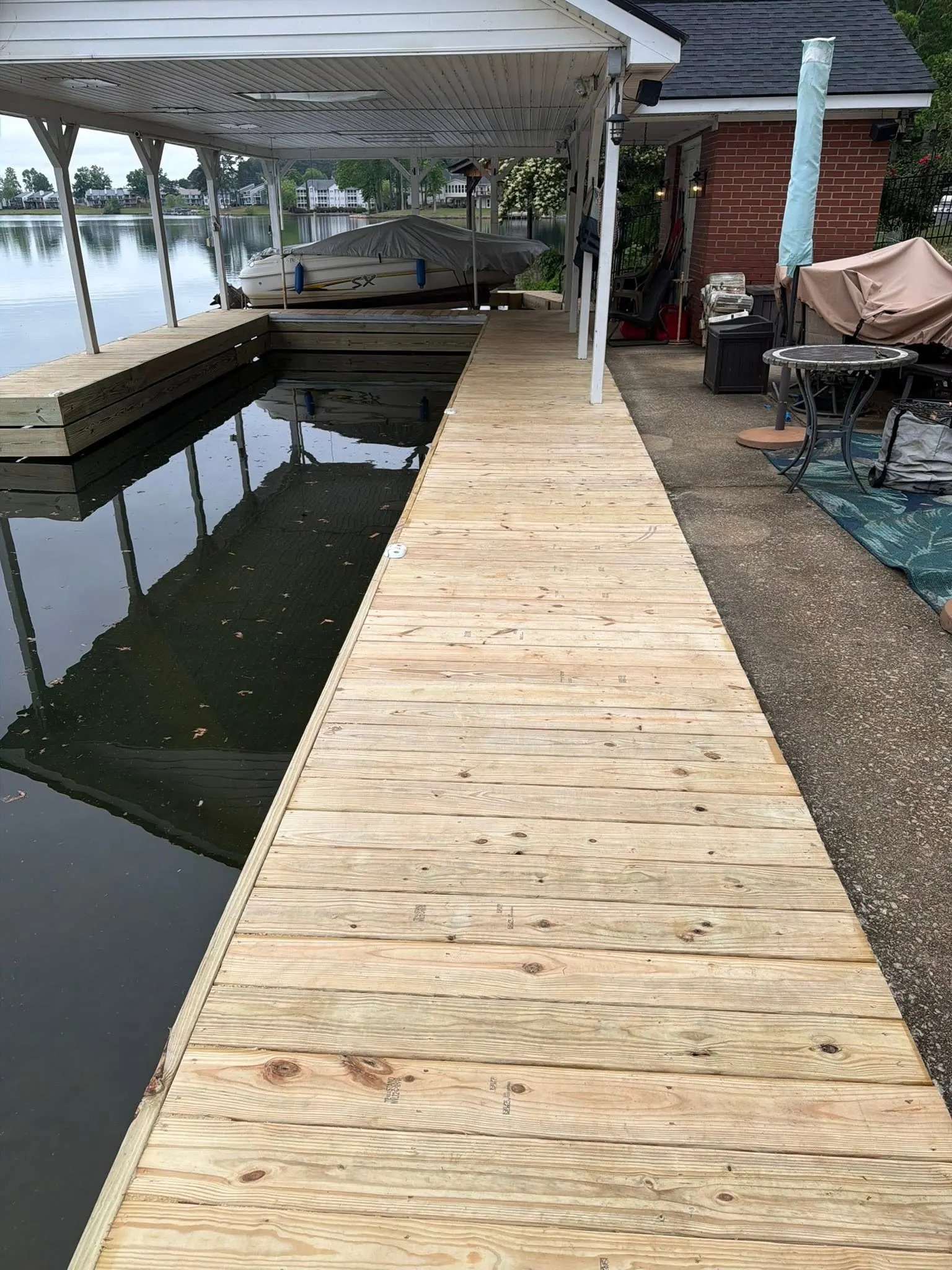New pressure-treated decking and fascia board on a boardwalk running out to a covered boat slip on a West Georgia lake