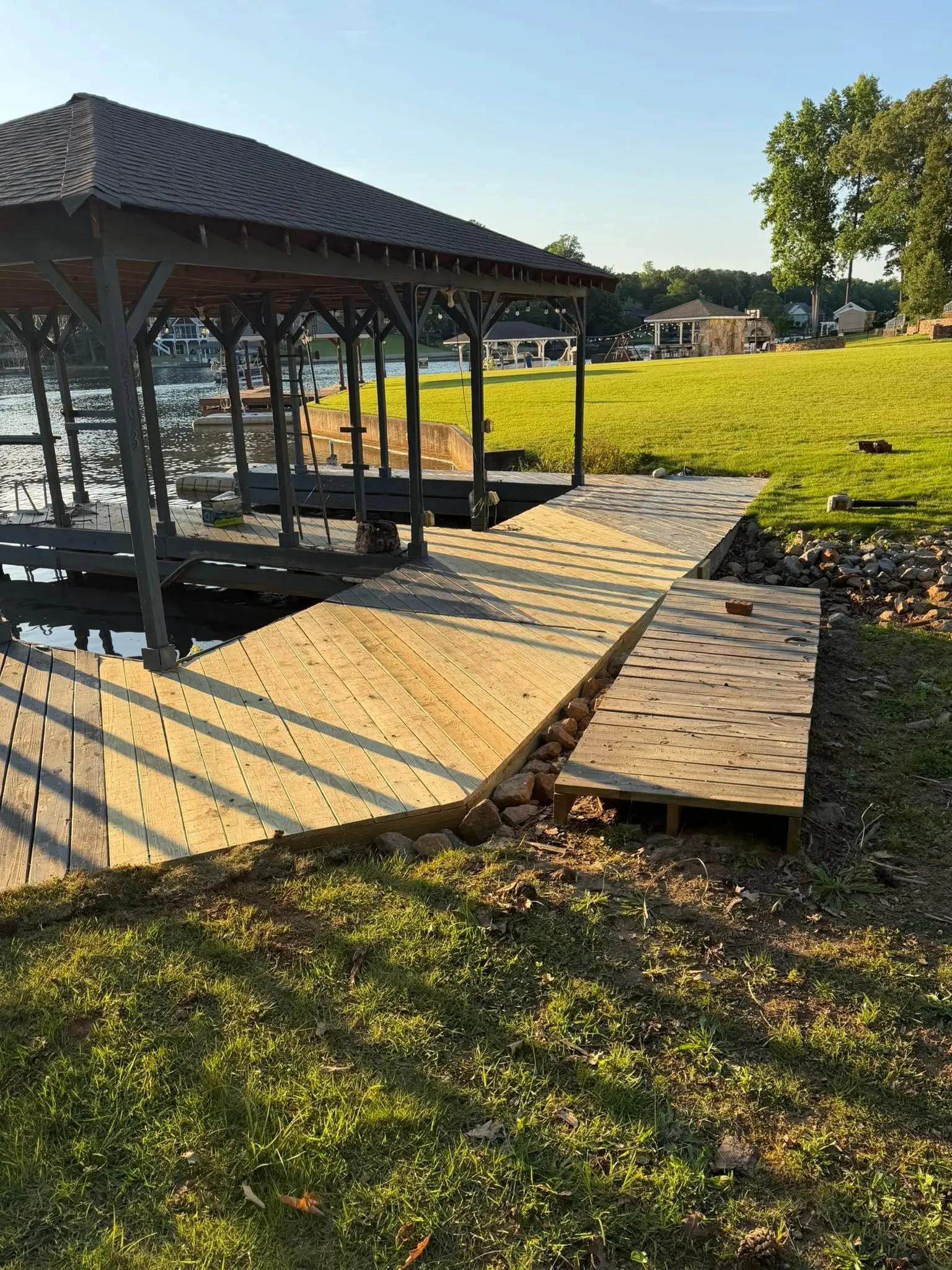 Repaired dock apron with new boards beside a covered boathouse