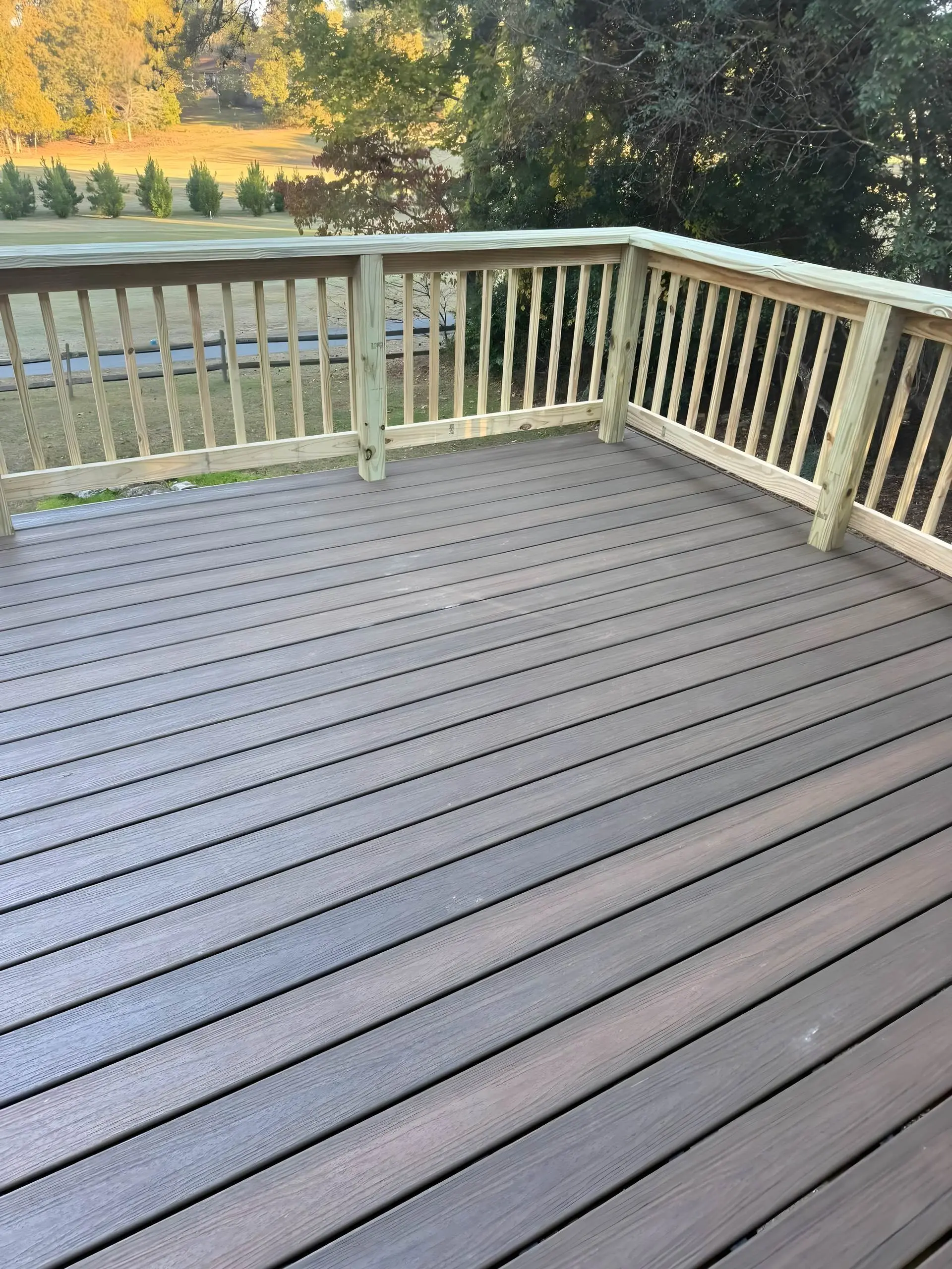 Composite deck flooring with pressure-treated railings overlooking a golf course
