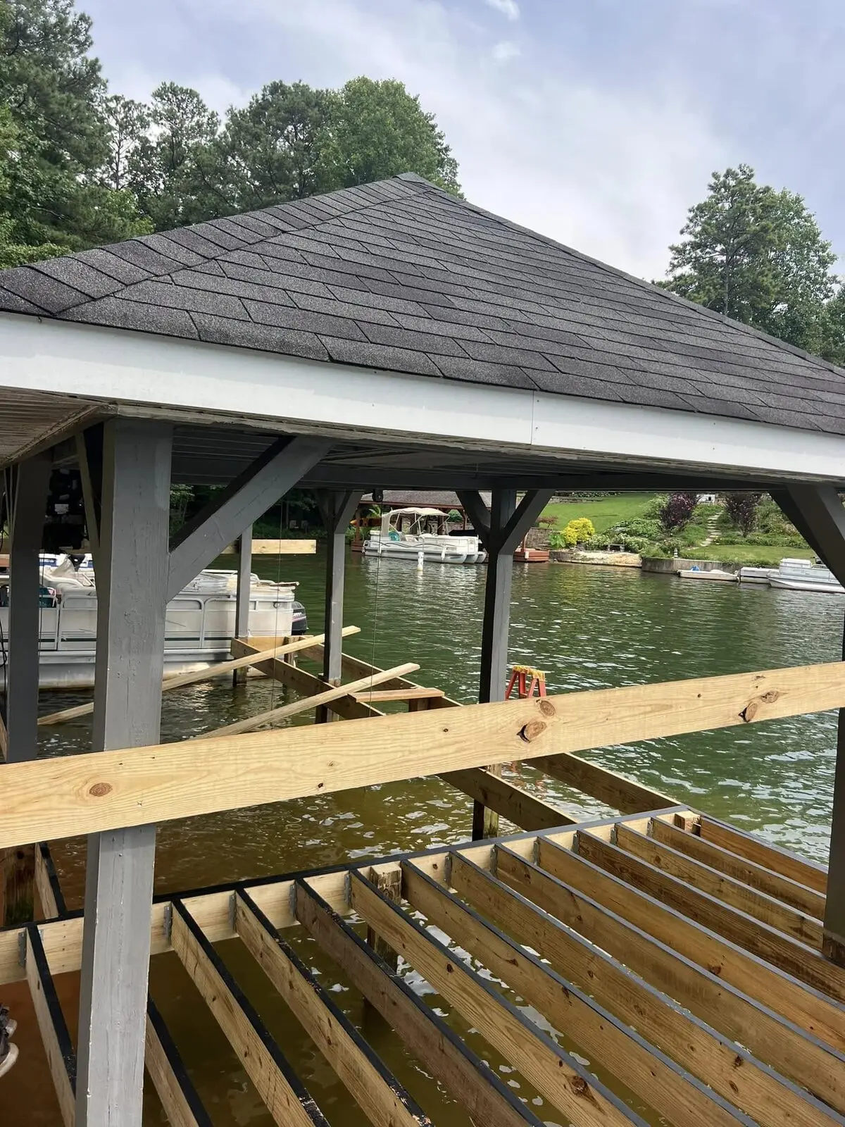 New dock joists set on galvanized hangers under a covered boathouse