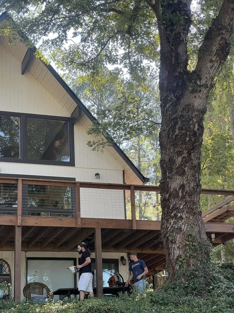 Crew at work under an elevated stained deck with cable rail that wraps the side of an A-frame home