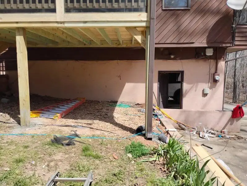 Under-deck rebuild in progress: new pressure-treated posts and joists over an old patio