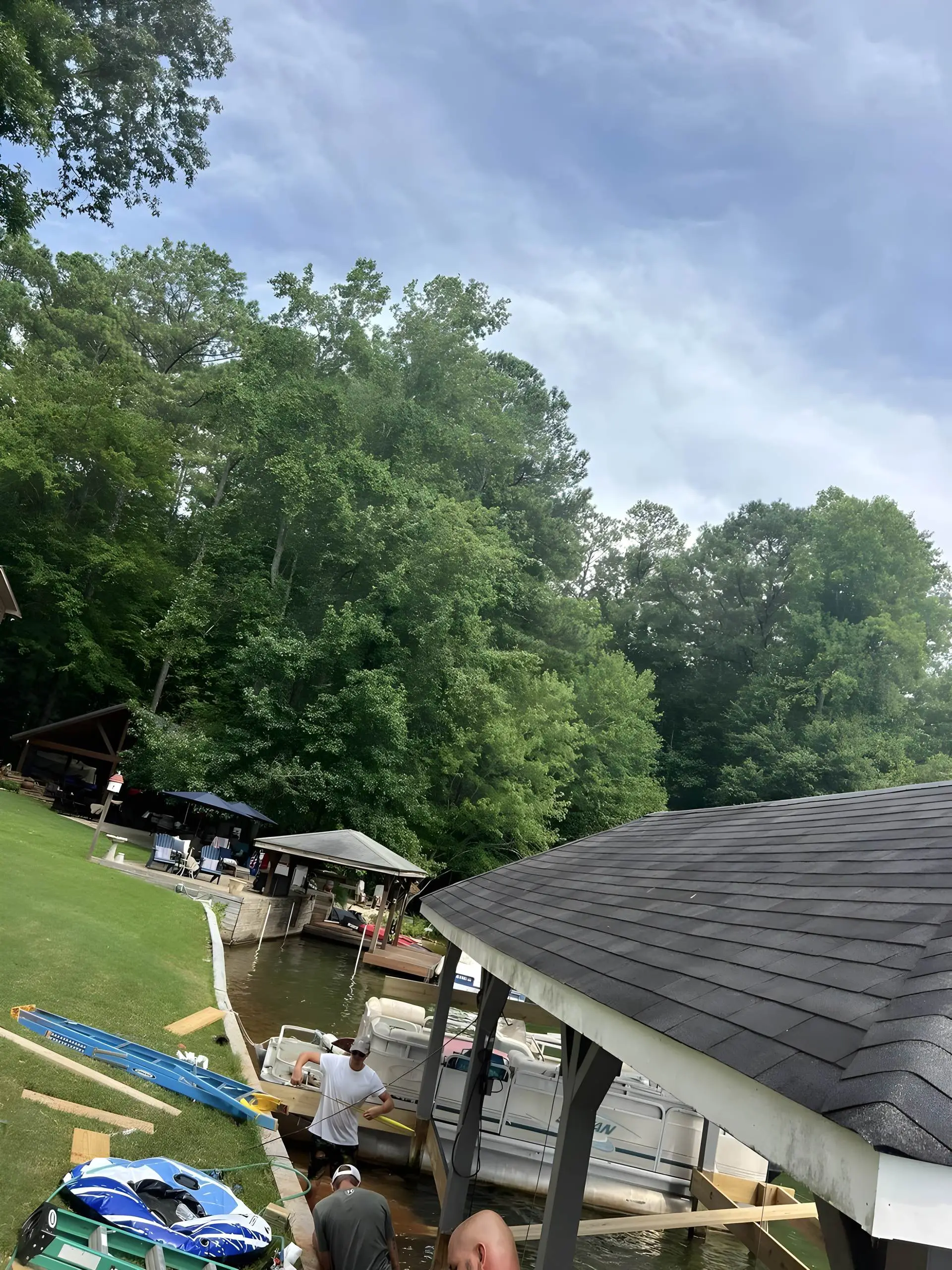 Crew framing a dock and boathouse while standing in the lake, boats moored nearby