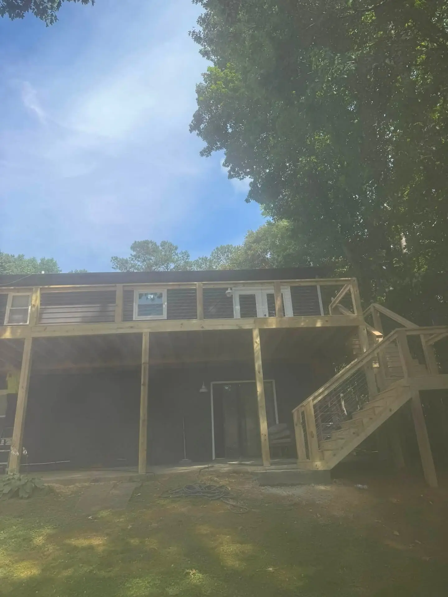 Elevated screened porch under construction with a new staircase down to the yard