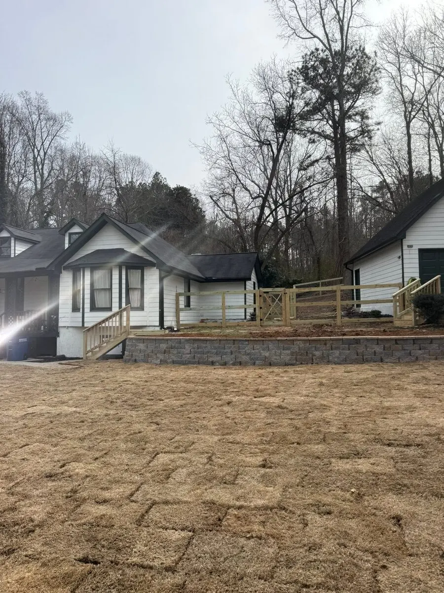 Completed retaining wall, farm fence, new stairs, and fresh sod across a Villa Rica yard