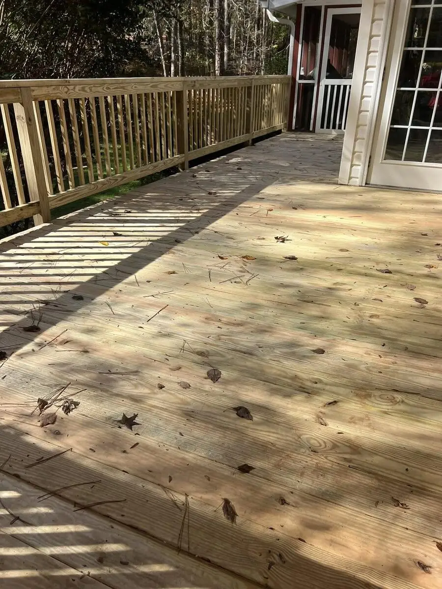 New pressure-treated deck built at a red farmhouse with a screened porch