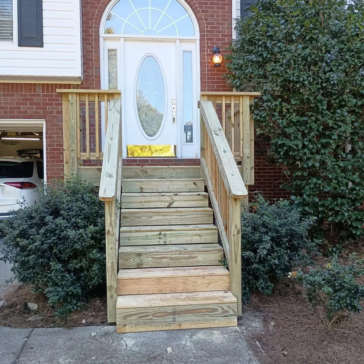 New pressure-treated deck stairs and railing built to a brick home's front door