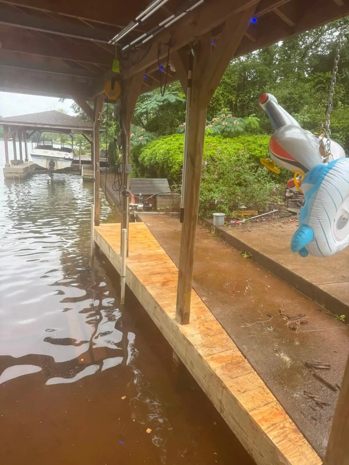 Freshly replaced pressure-treated dock decking beside a covered boathouse slip, boat moored alongside