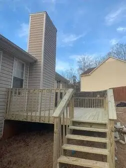 Clean pressure-treated deck attached to a tan-sided home under a blue sky