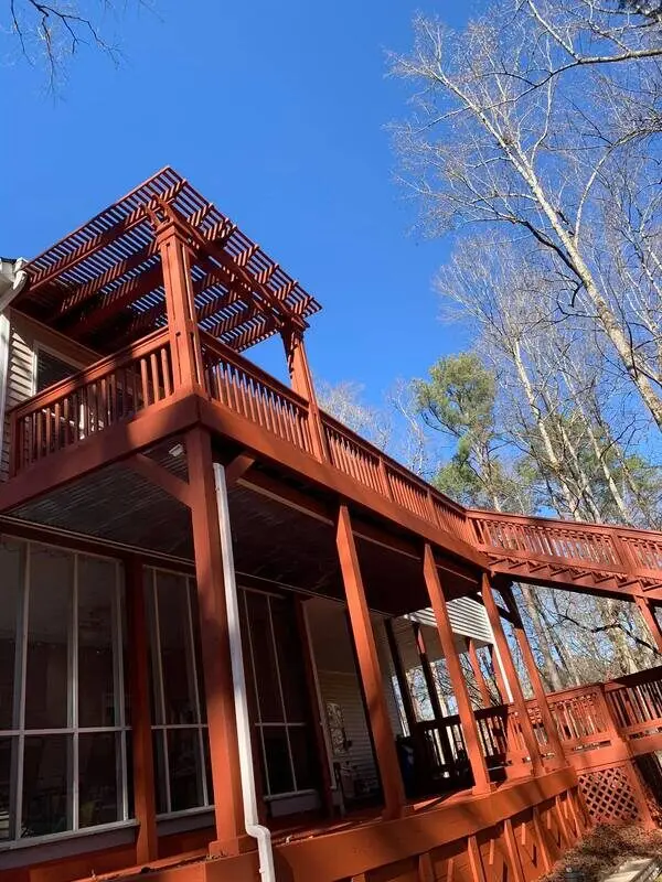 Red-stained multi-level deck with a pergola over a screened porch