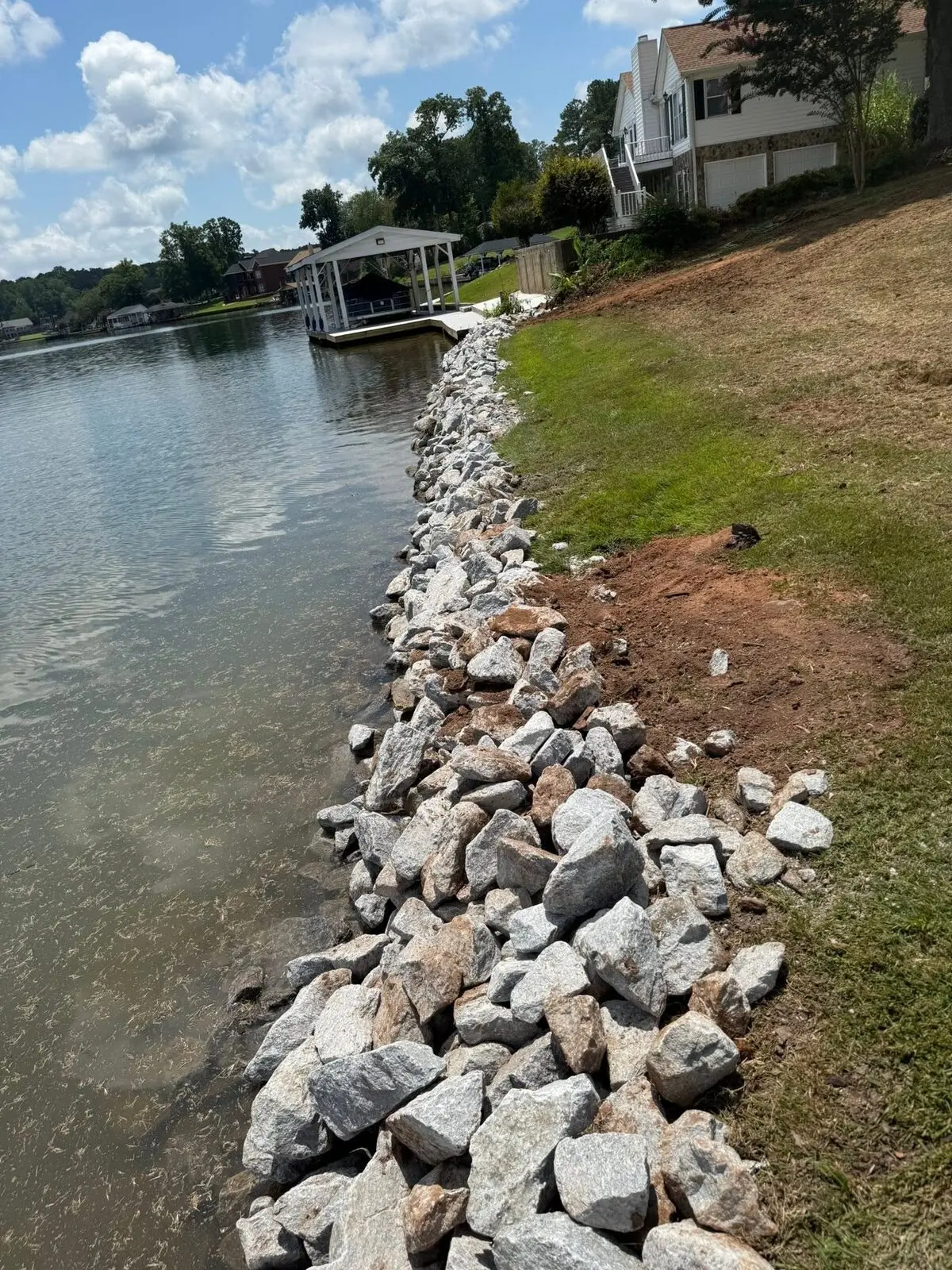 Completed rip-rap stone seawall along a lake bank in Fairfield Plantation