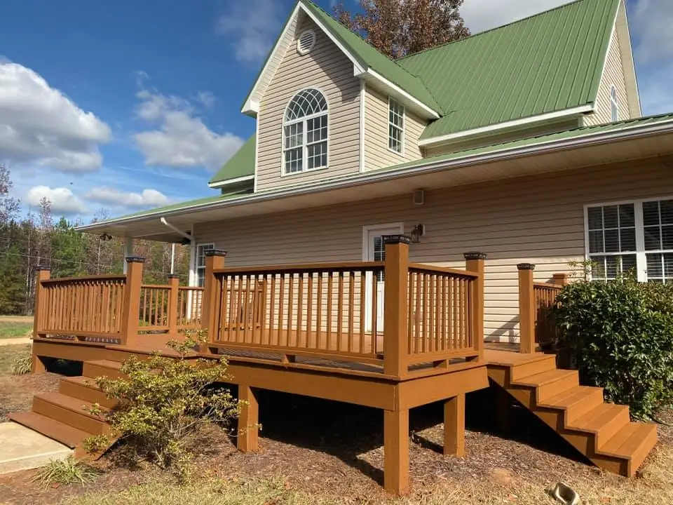Stained wood deck with stairs at a house with a green metal roof